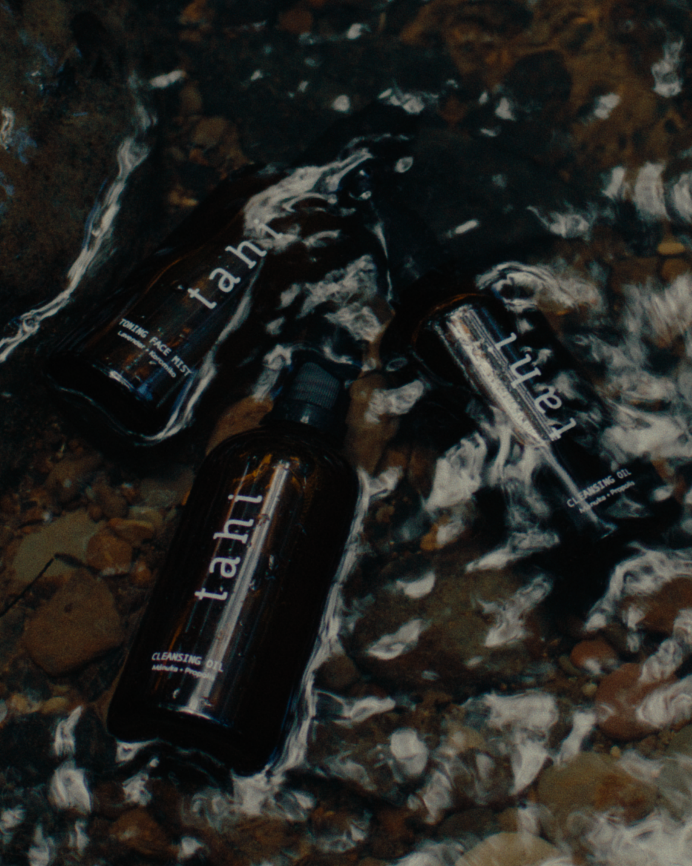 Three Tahi skincare bottles on a textured surface