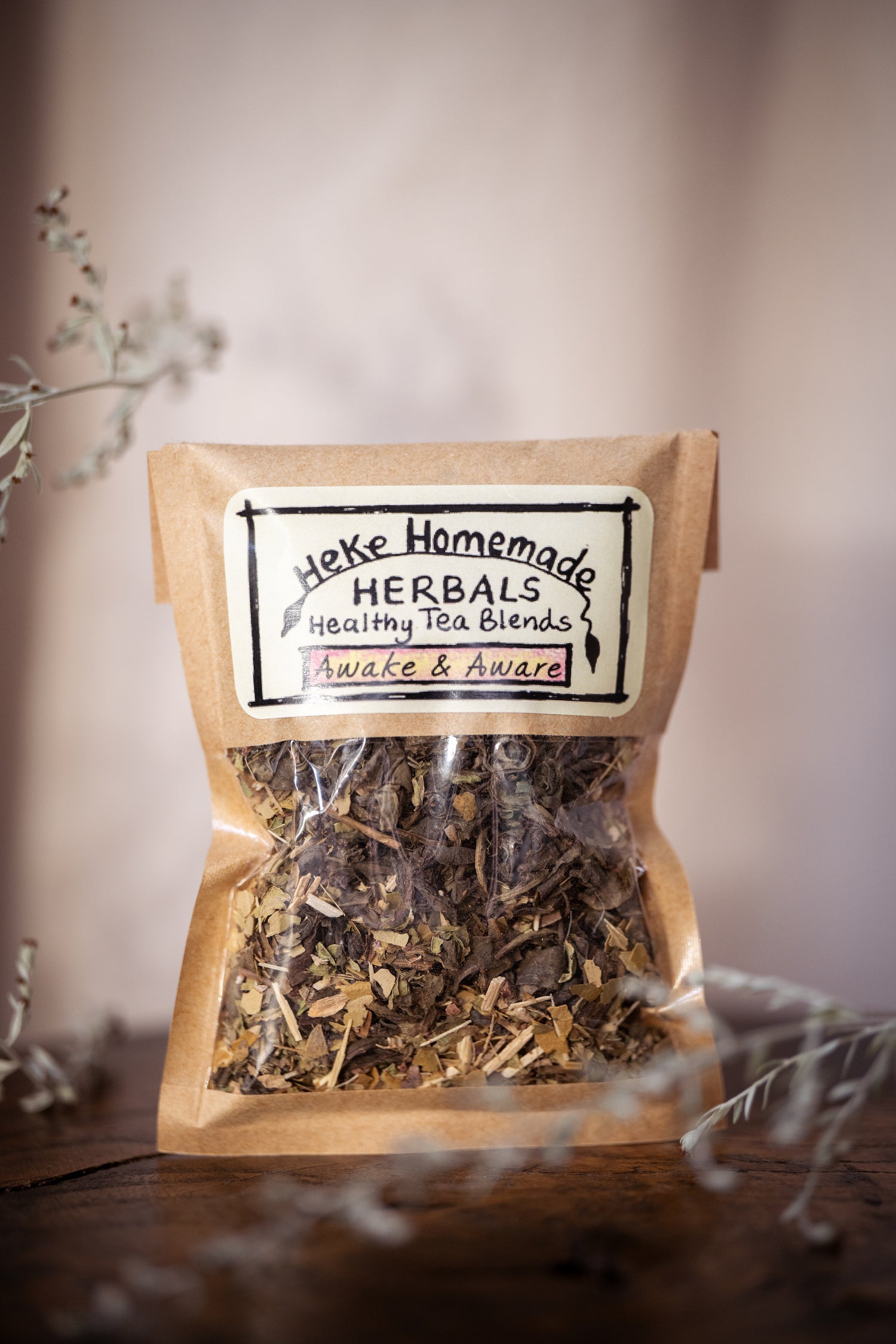 Packaged tea blend from Heke Herbals with visible dried herbs through the transparent packaging, labeled as 'Awake and Aware Tea'.
