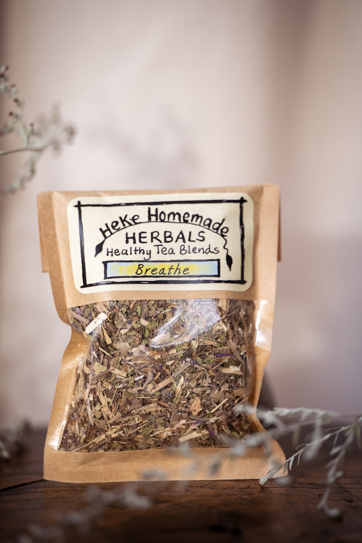 Packaged tea leaves and herbs in a clear bag with a label reading 'Heke Homemade Herbals Breathe Tea'.
