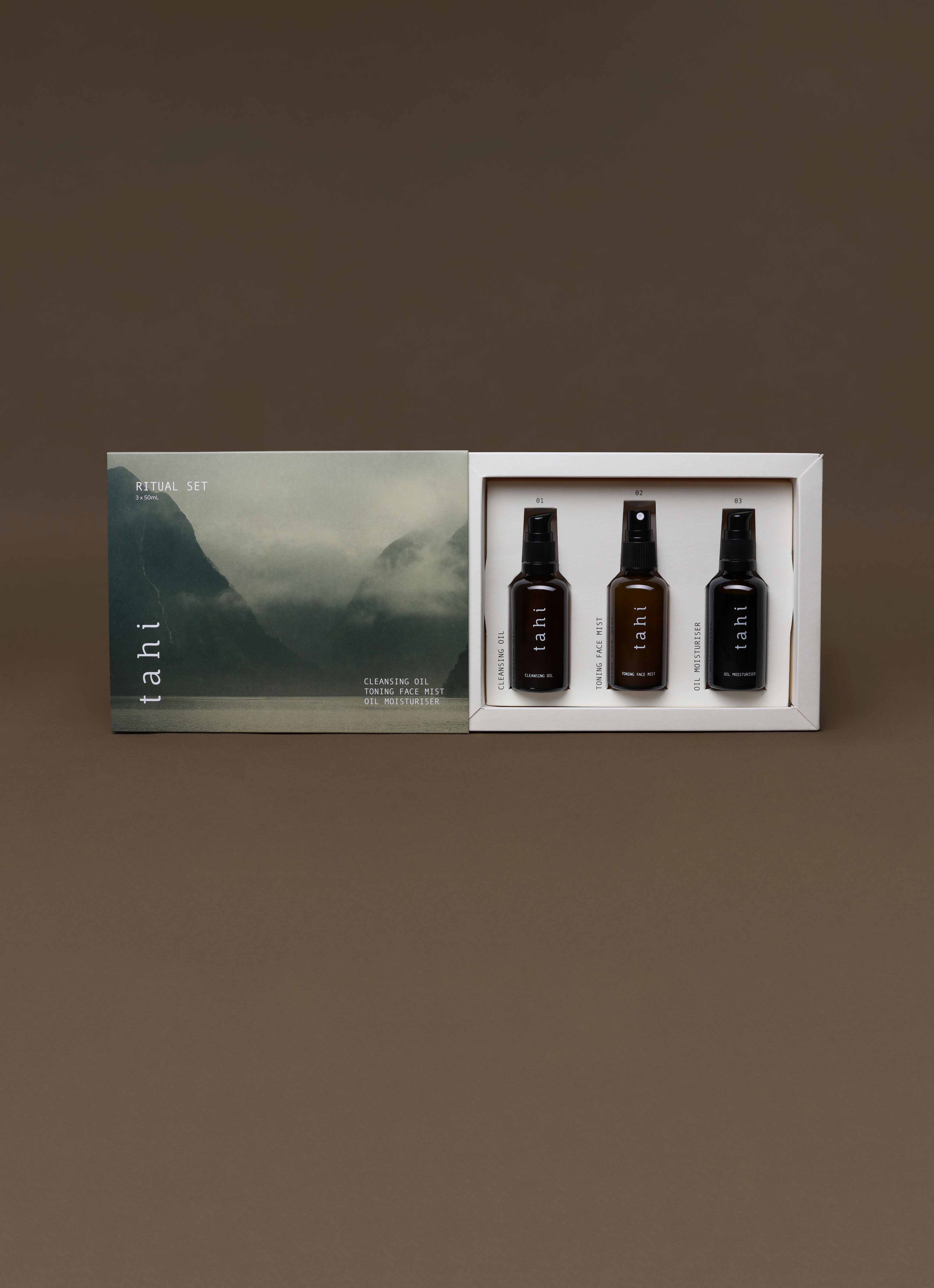 Three bottles of TAHI skincare in a box with a scenic label on a brown background