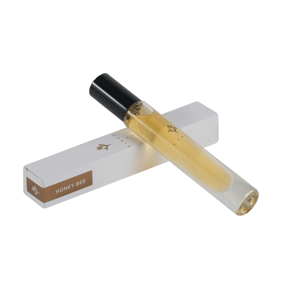 A small, clear glass vial of Honey Bee perfume, with a black cap and a white label that reads 'HONEY BEE'.