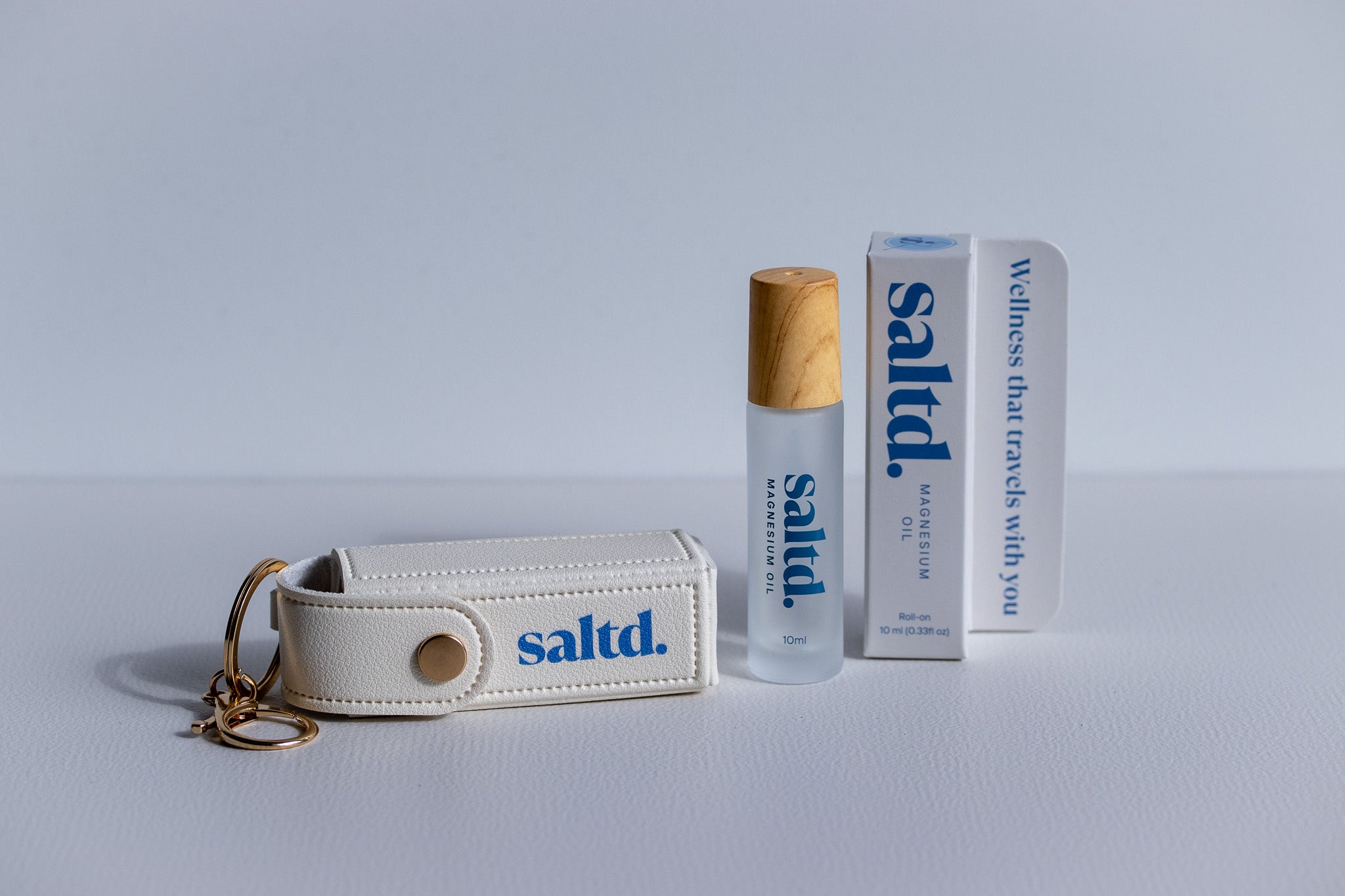 White 'saltd' keychain, bottle, and box on a light gray background