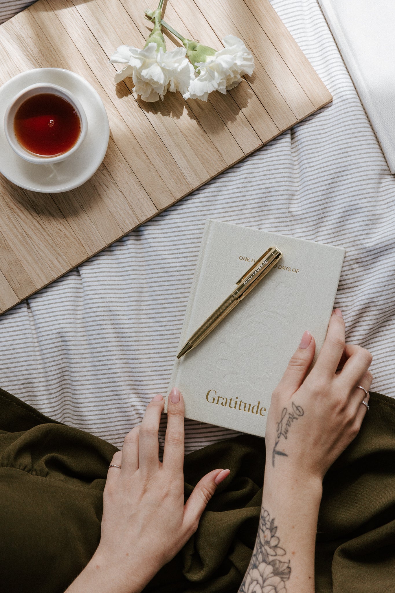 Olive and Page gold 'press pause' pen resting on a journal