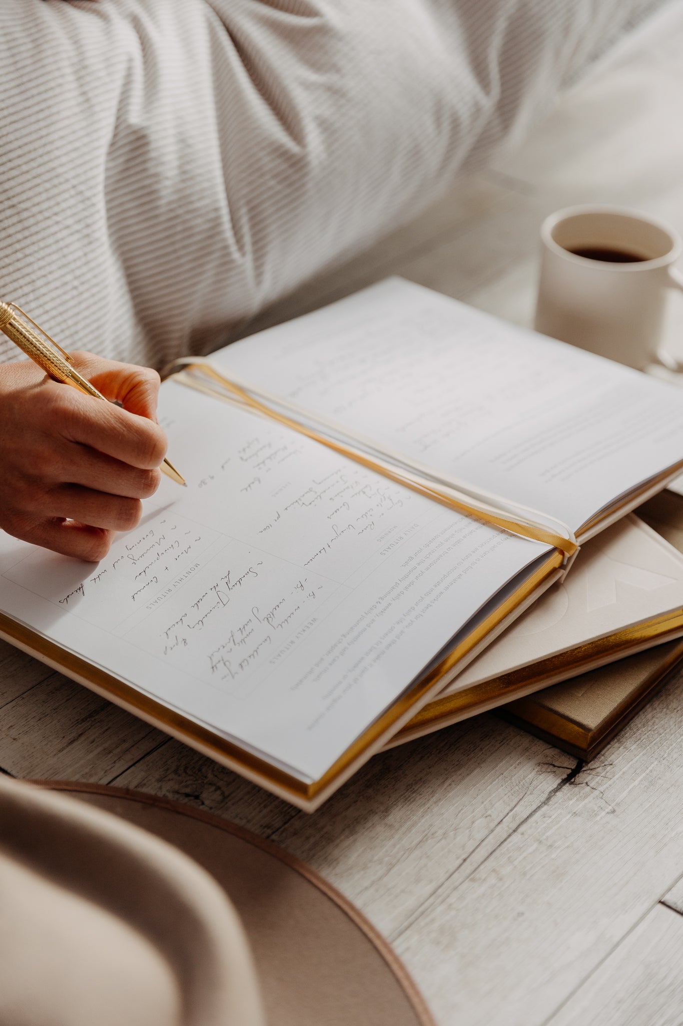 Person writing in a journal with a cup of coffee beside them