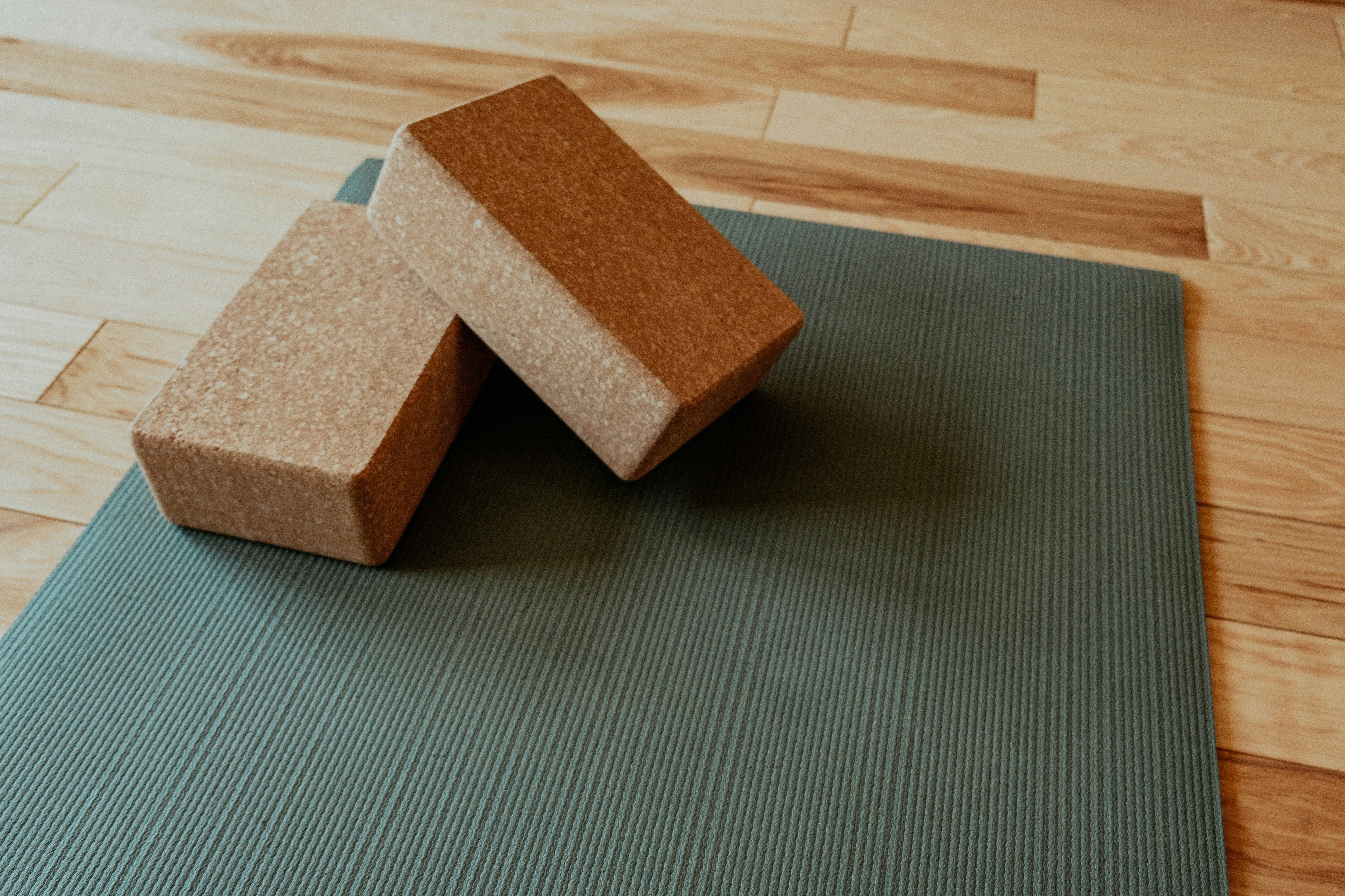 Two cork yoga blocks on a yoga mat in a wooden room.