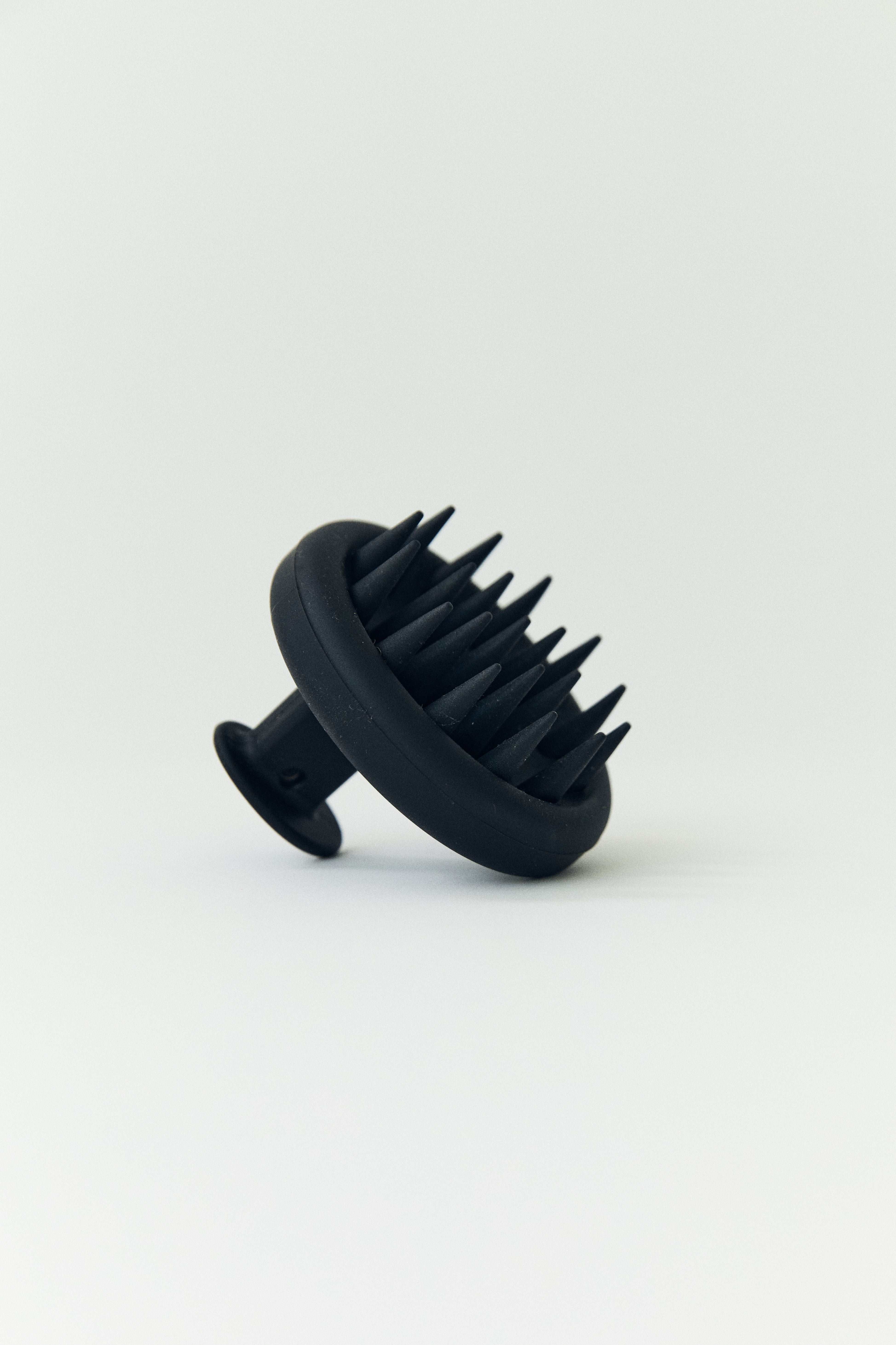 Black scalp hair massager on a white background