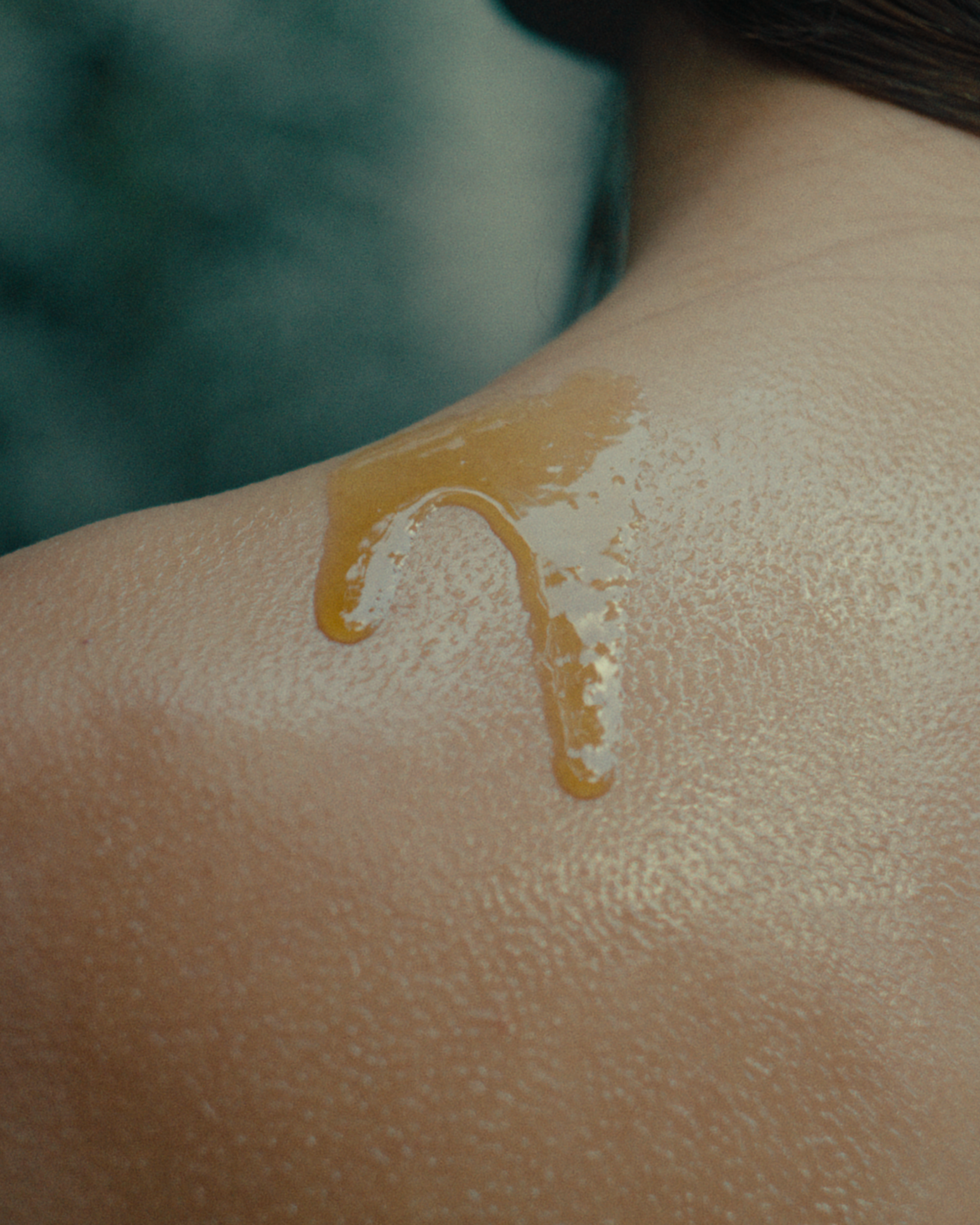 Close-up of a person's shoulder with a Tahi cleansing oil applied to the skin.
