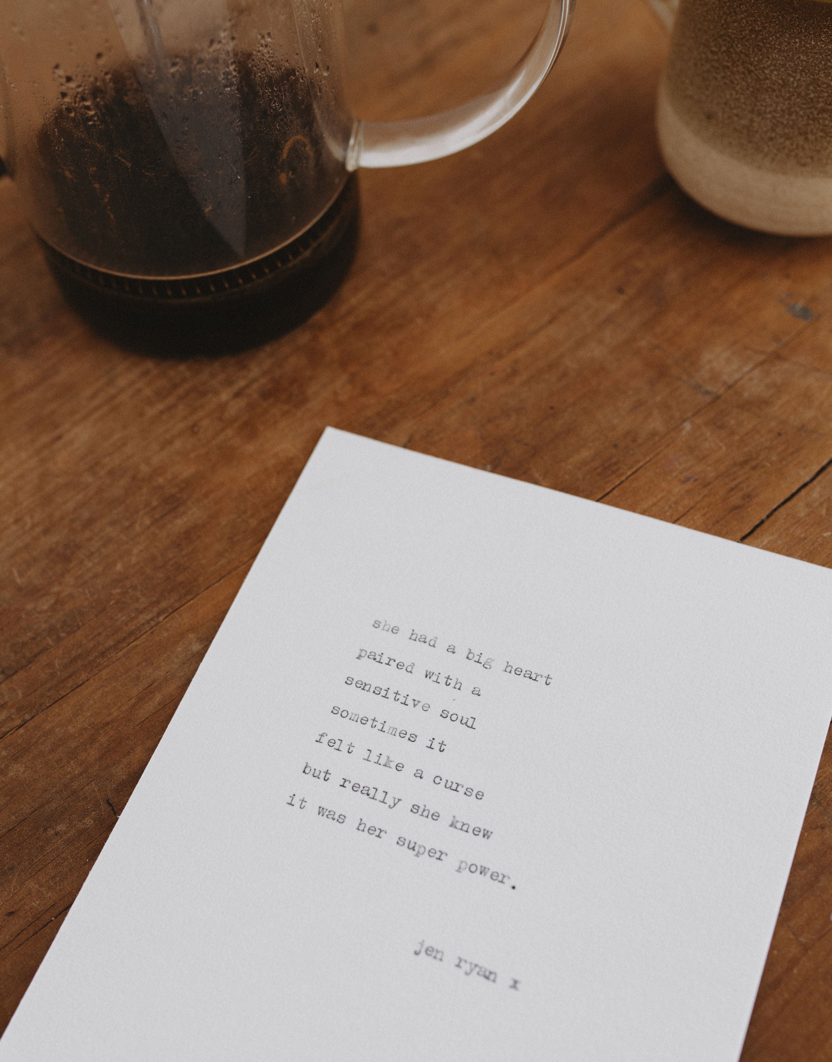 Sheet of paper with text on a wooden surface next to a coffee maker.