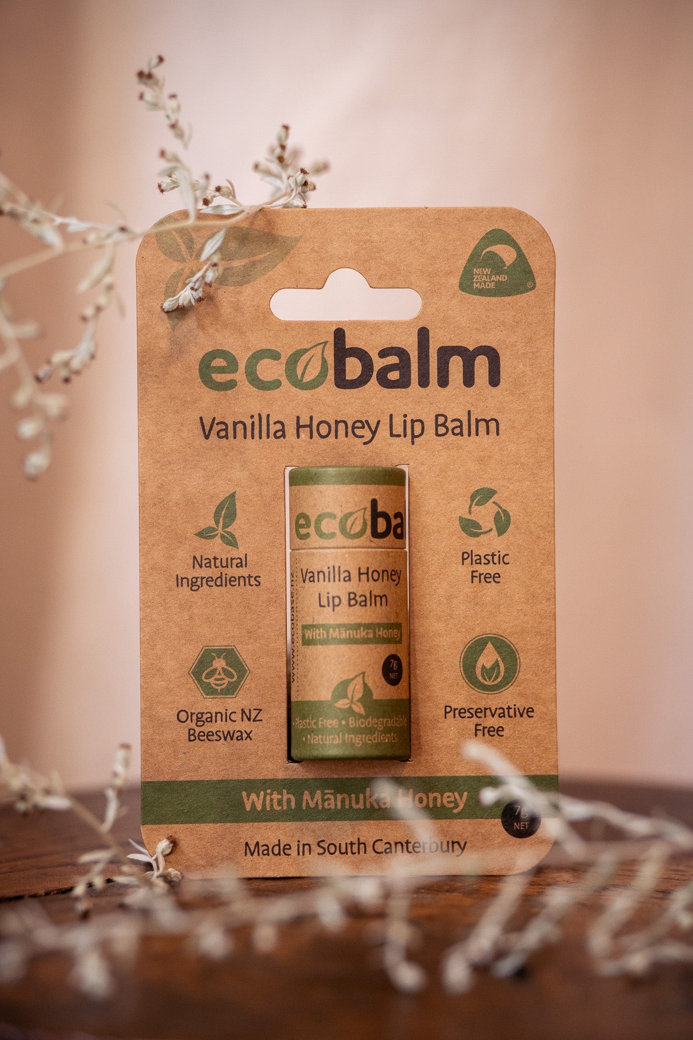 A stick of ecobalm Vanilla Honey Lip Balm packaged in a cardboard sleeve with product information and branding visible.