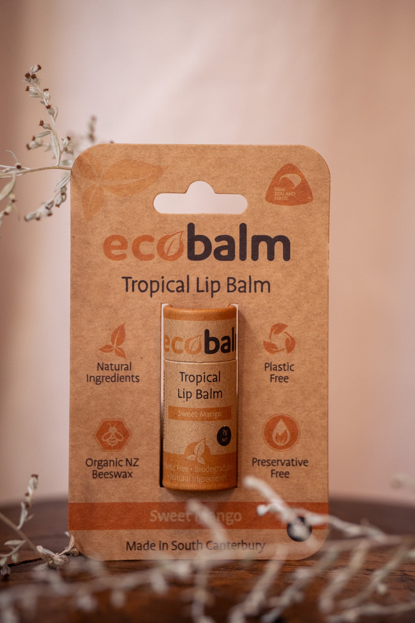 A packaged ecobalm Tropical lip balm with its natural ingredients listed on the package, including sweet almond oil, organic beeswax, and mango flavoring oil.