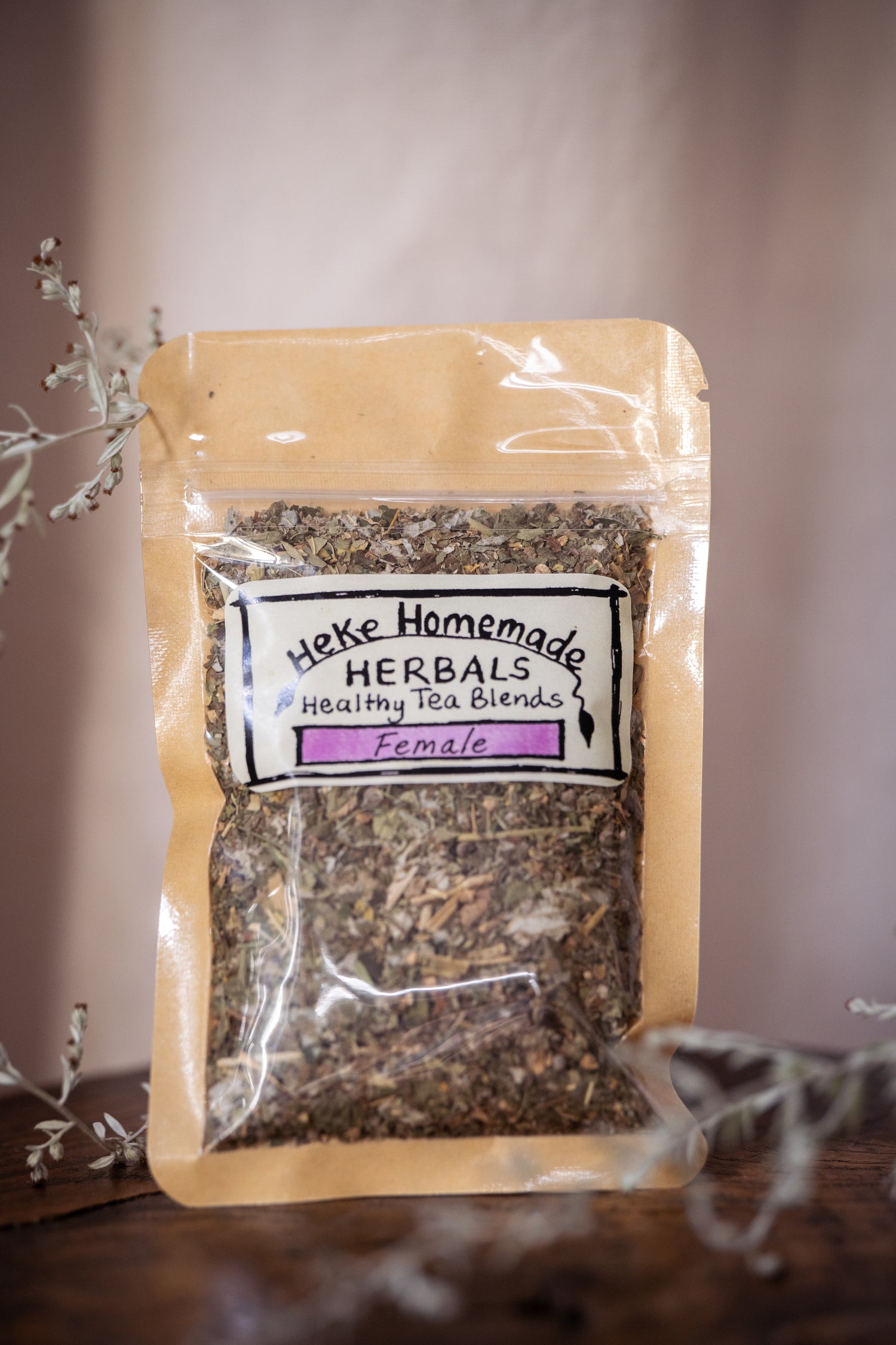 Packaged herbal tea blend labeled 'Female' from Heke Herbals, featuring a natural brown paper bag with a clear window showing the product inside.