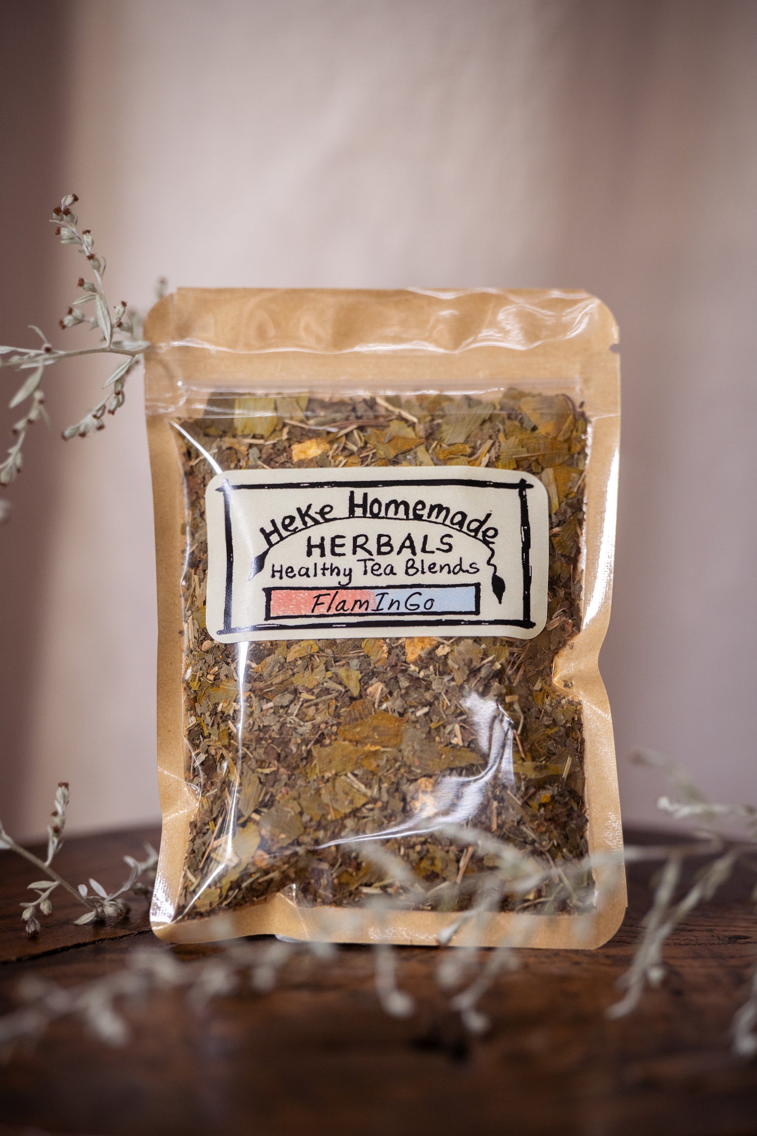 Packaged tea blend from Heke Herbals with visible dried herbs through the clear plastic, labeled as FlaminGo Tea.