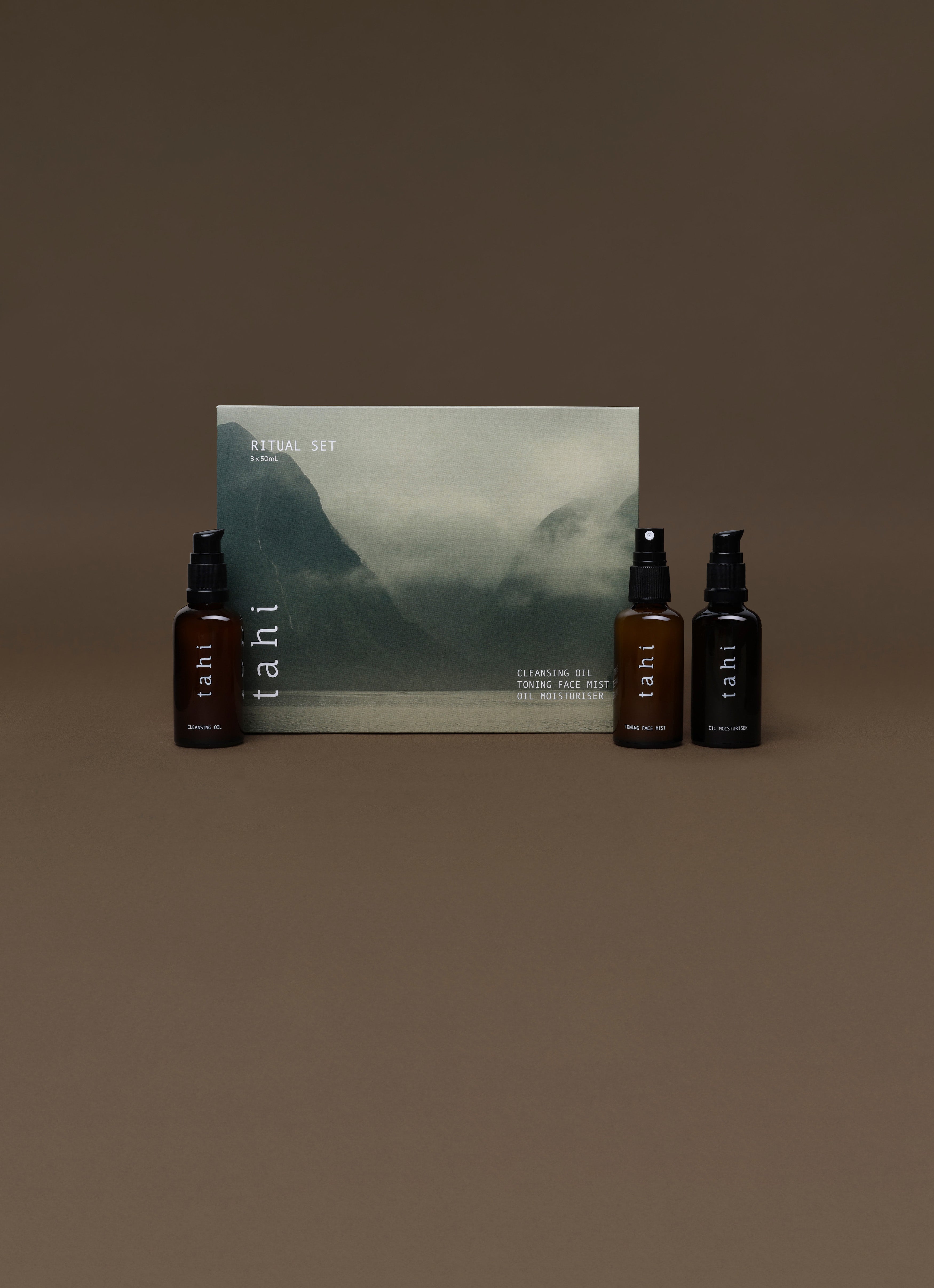 Three bottles and a box of TAHI skincare with a mountain graphic on a brown background