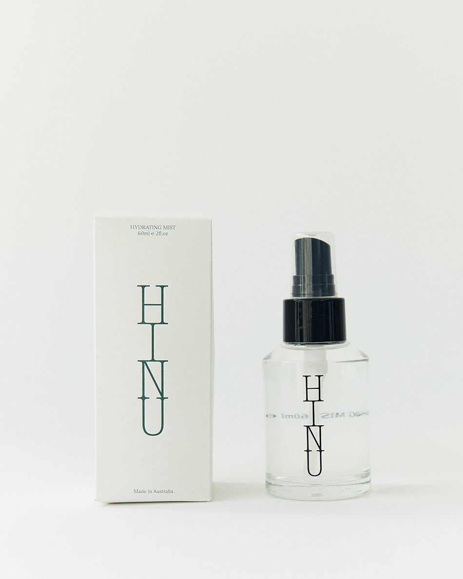 Clear spray bottle with black cap and 'HINU' branding next to a matching box on a white background - HINU hydrating hair mist
