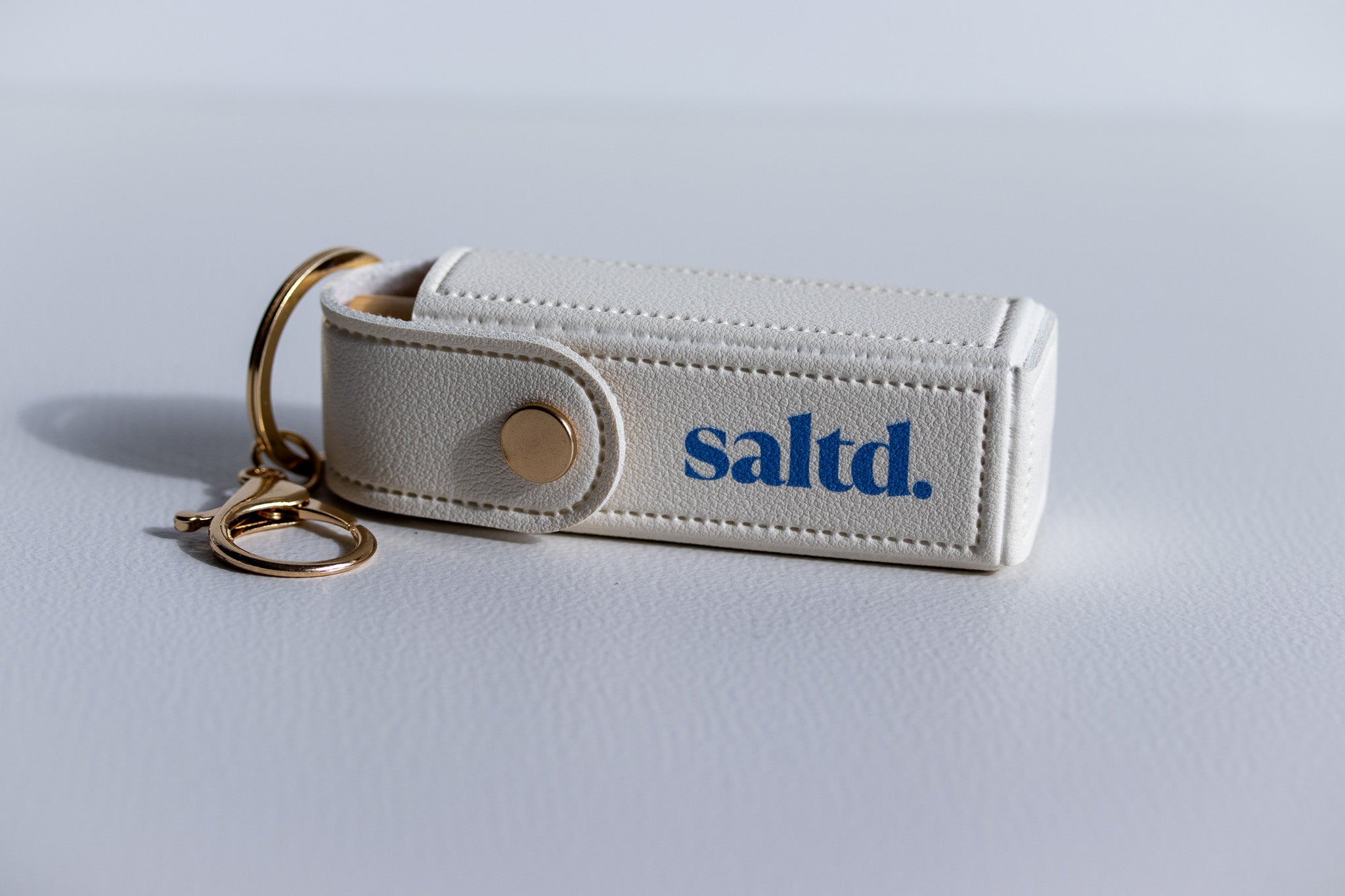 White keychain with 'saltd.' logo on a light gray background
