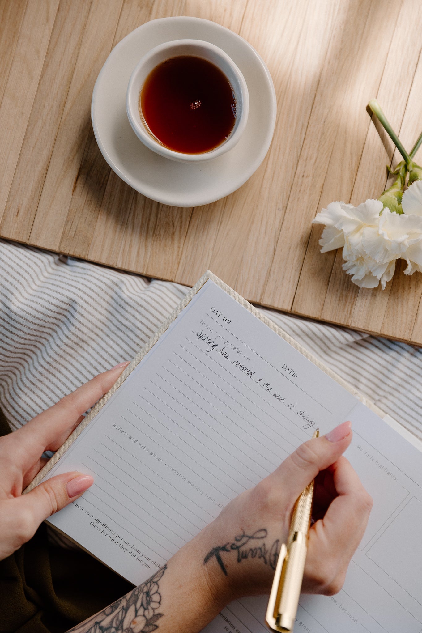 open gratitude journal with hand holding a pen