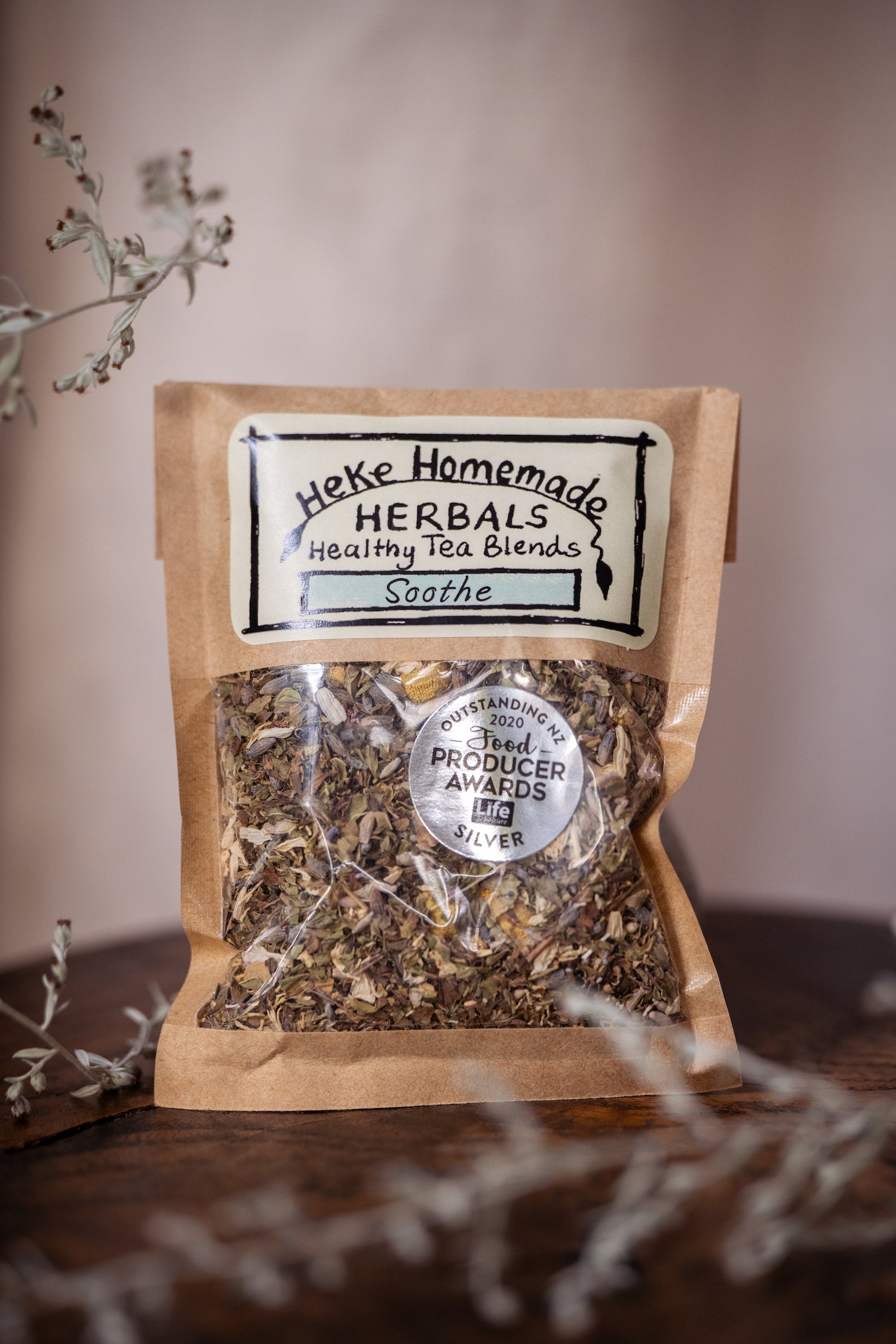 Packaged loose tea blend from Heke Herbals with visible dried herbs through the transparent packaging, labeled as 'Soothe Tea'.