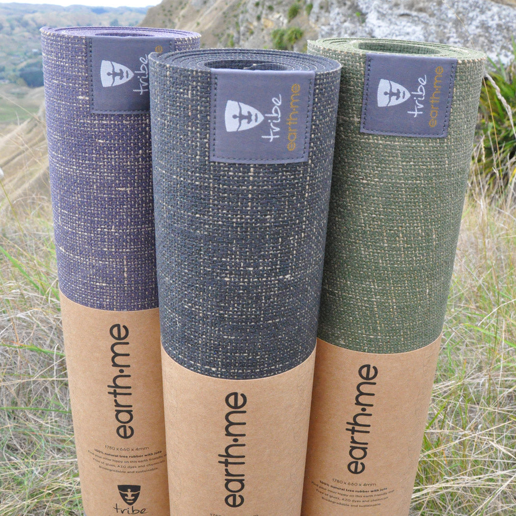 Three rolled-up yoga mats with 'earth.me' branding on a natural background.